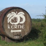 Cidrefass mit dem Logo der Cidrerie Kerné als Wegweiser am Straßenrand